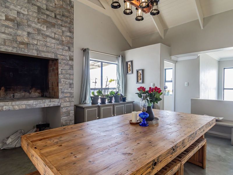 Spacious living area featuring a striking stone-clad fireplace, vaulted ceilings with exposed rafters, and polished concrete flooring, creating a warm and inviting atmosphere.
