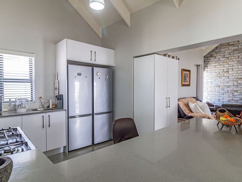 Modern open-plan kitchen featuring stone countertops, gas cooktop, and built-in cabinetry, flowing into a living area with a striking exposed stone feature wall.
