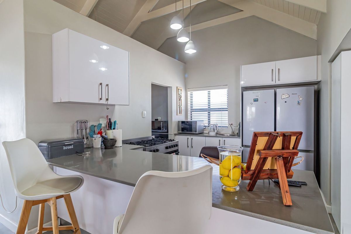 Modern kitchen featuring vaulted ceilings, stone countertops, built-in cabinetry, and a gas hob, creating a bright and functional culinary space.