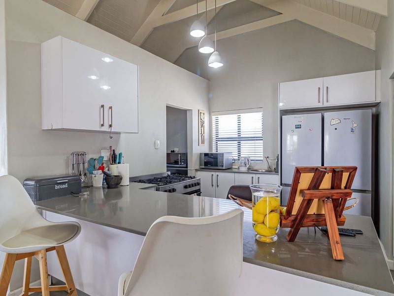 Modern kitchen featuring vaulted ceilings, stone countertops, built-in cabinetry, and a gas hob, creating a bright and functional culinary space.