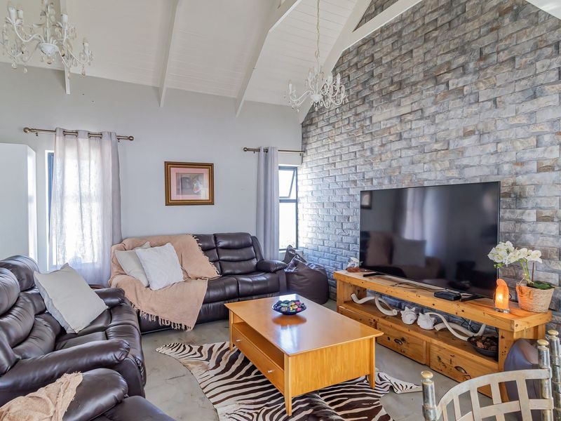 Spacious living room featuring a high vaulted ceiling with exposed rafters and a striking stone feature wall.