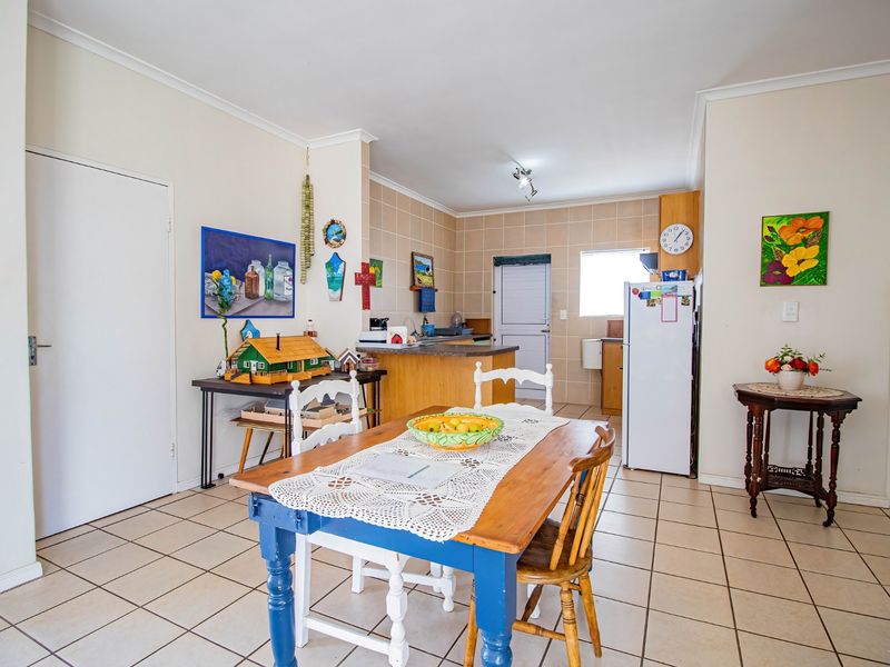 Open plan kitchen and dining area featuring tiled flooring, neutral walls, and functional cabinetry, offering a practical layout for daily living.