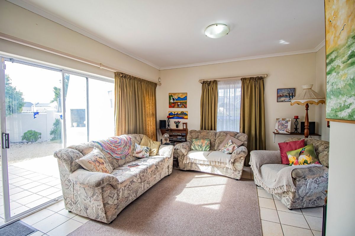 A living room featuring tiled flooring and a large sliding glass door providing access to the outdoor patio area.