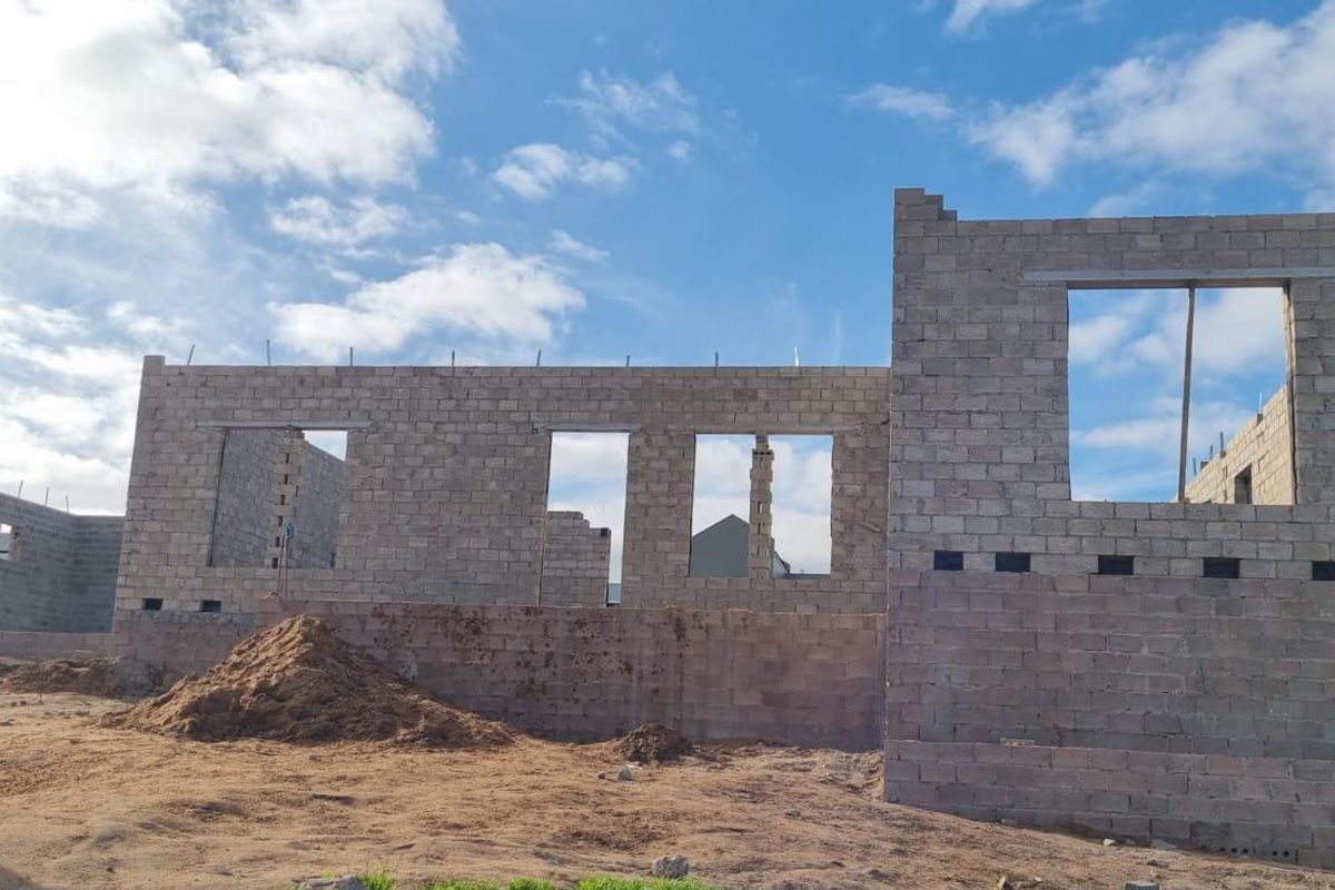 A view of a residential property currently under construction, featuring exposed concrete block walls and open window frames.