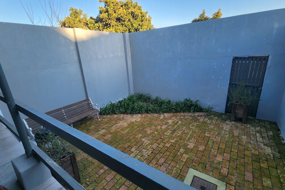 A private rear courtyard featuring brick paving and high boundary walls, offering a secluded outdoor space with potential for landscaping improvements.