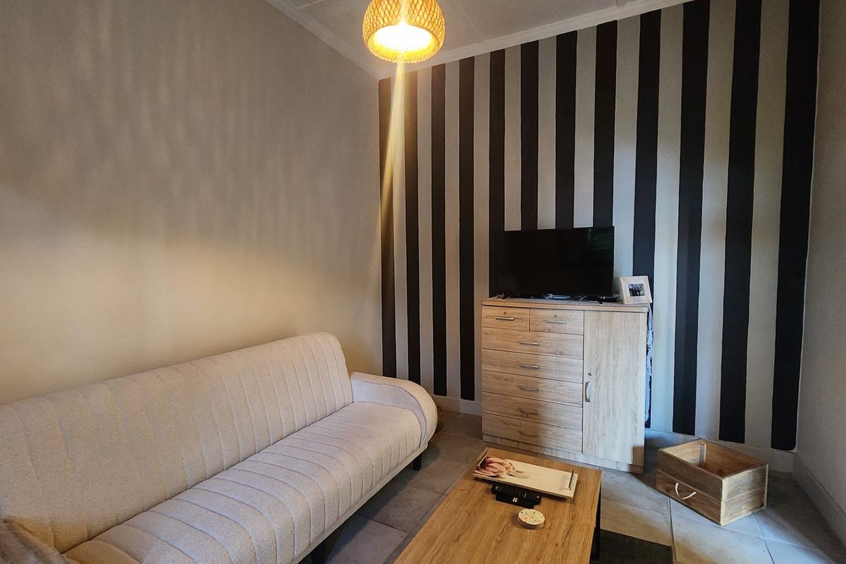 A cozy living room featuring tiled flooring and a bold striped feature wall, providing a comfortable space for relaxation.