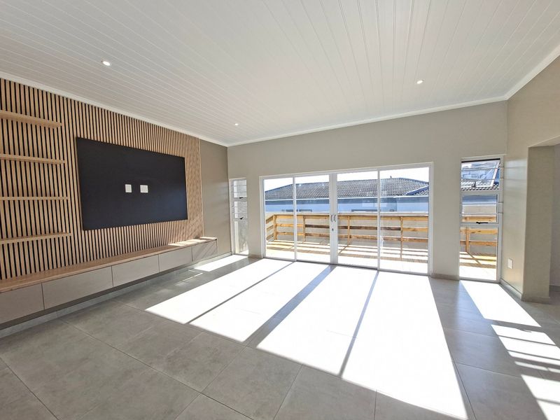 Spacious living room featuring a modern slatted timber feature wall, built-in cabinetry, large sliding glass doors, and neutral tiled flooring.