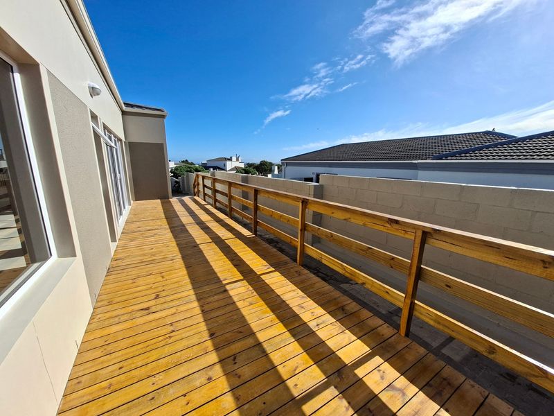 Spacious elevated timber balcony featuring a wooden balustrade and direct access to the interior through sliding glass doors.