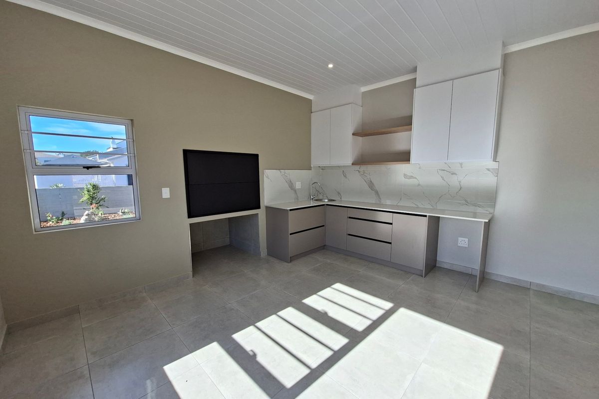 Modern kitchen area featuring sleek cabinetry, marble-look splashback, integrated sink, and a built-in braai, finished with neutral floor tiles and a clean ceiling design.