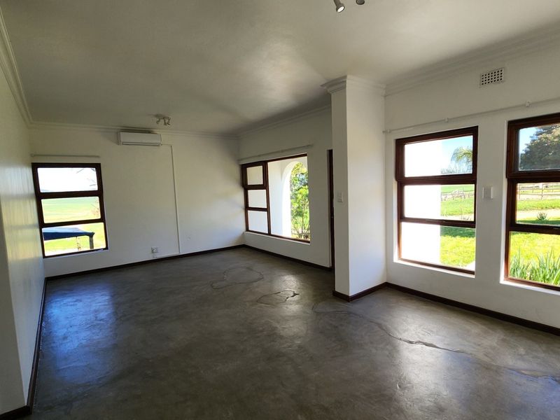 Spacious, light-filled living area featuring polished concrete floors, timber-framed windows, and a split-system air conditioner, offering a blank canvas for interior design.