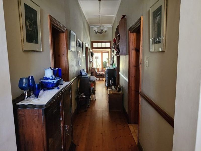 A traditional hallway featuring polished timber flooring, classic timber door frames, and decorative ceiling detailing, connecting the main living areas of the home.