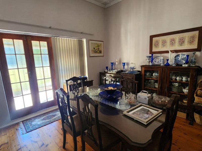 A dining room featuring polished timber flooring and classic french doors providing access to the exterior.