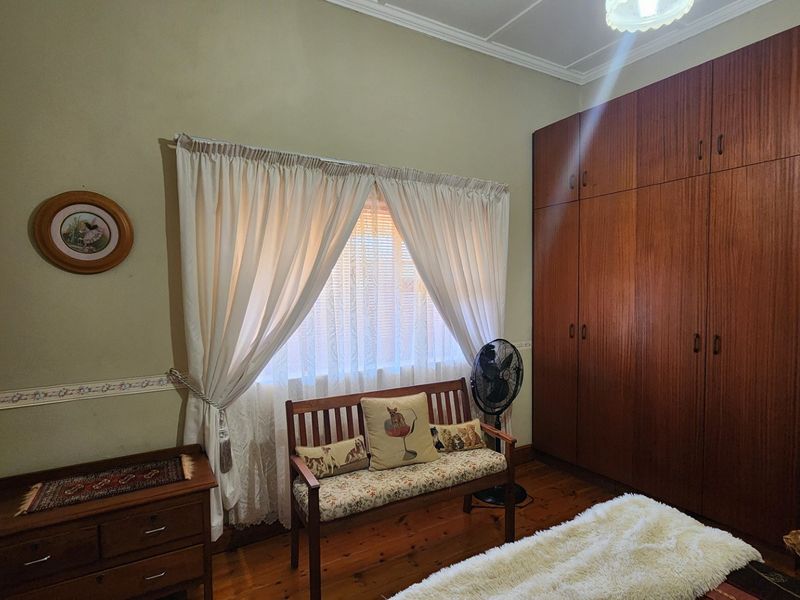 A bedroom featuring polished timber flooring, crown molding, and a large floor-to-ceiling built-in wooden wardrobe.