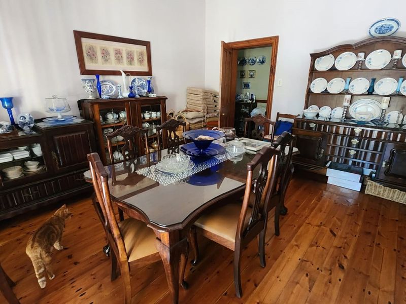 A traditional dining room featuring polished timber flooring and access to an adjacent room.