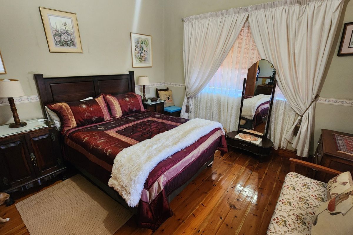 A cozy bedroom featuring polished hardwood flooring and classic window treatments, offering a warm and traditional living space.