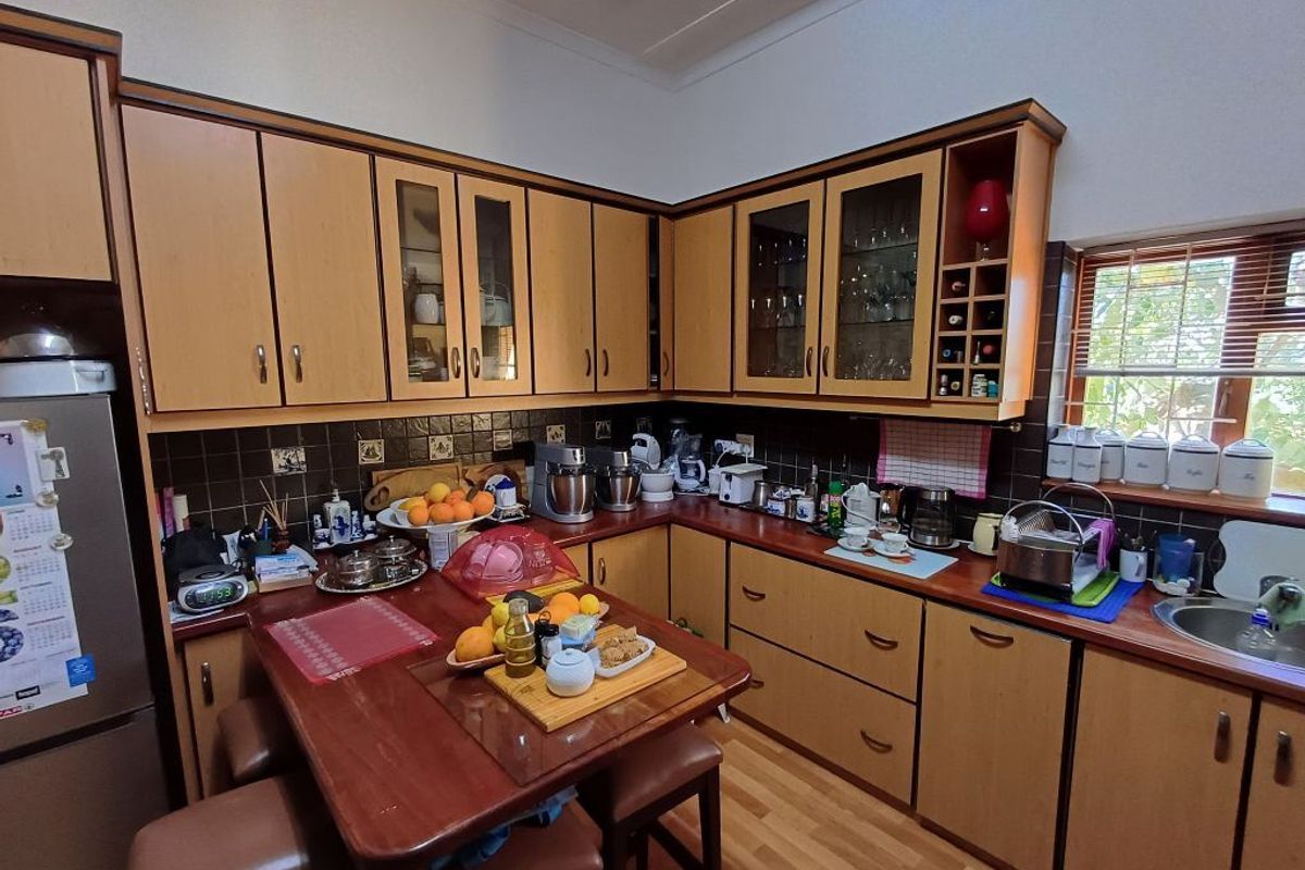 A functional kitchen featuring wood-look laminate cabinetry, tiled backsplash, and integrated storage solutions with a compact breakfast nook area.