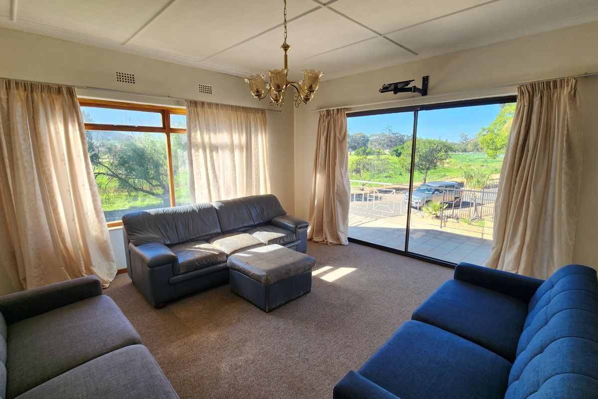Spacious living room featuring large sliding glass doors and a picture window, offering natural light and views of the surrounding landscape.