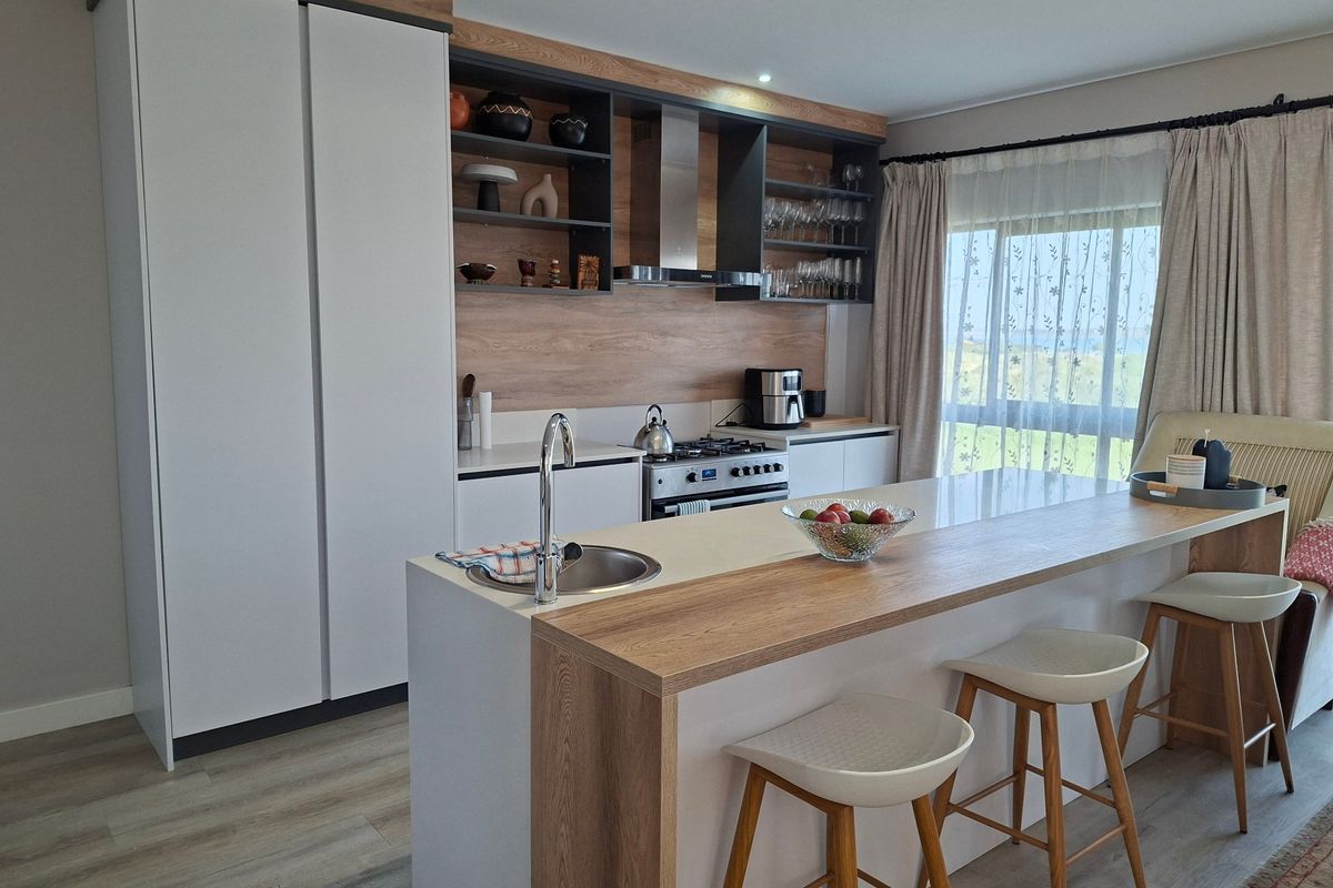 Modern kitchen featuring a central island with an integrated sink, sleek cabinetry, wood-tone accents, and a gas hob with an extractor fan.