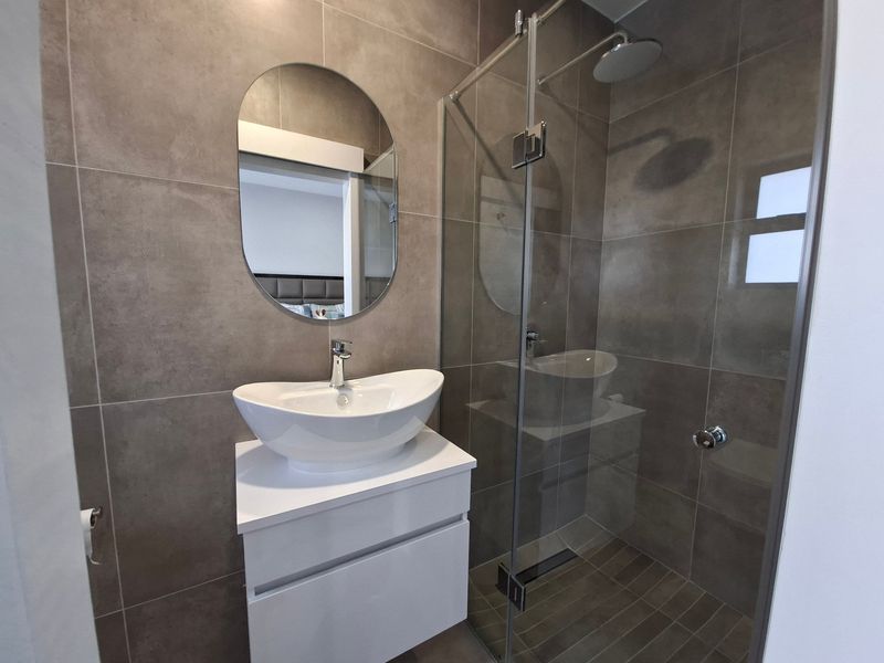 Modern bathroom featuring a floating vanity with a vessel sink, a spacious walk-in shower with a glass enclosure, and contemporary floor-to-ceiling wall tiles.