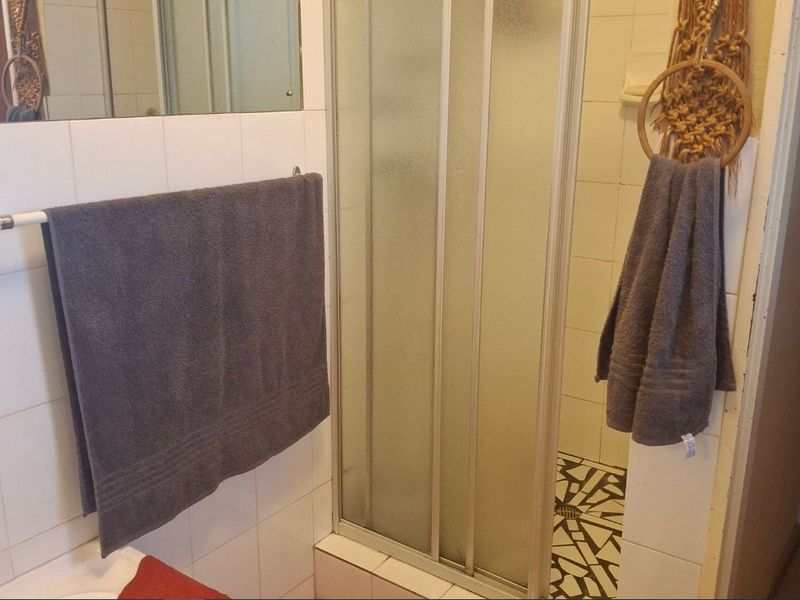 A dated bathroom featuring a shower enclosure with tiled walls and flooring, requiring cosmetic updates to improve the overall aesthetic.