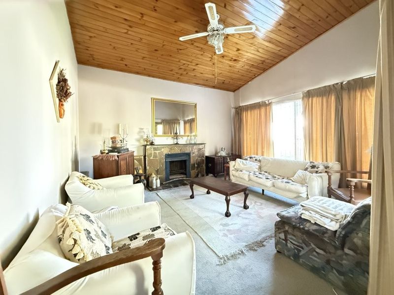 Spacious living room featuring a stone fireplace and a high timber-clad vaulted ceiling with an integrated ceiling fan.