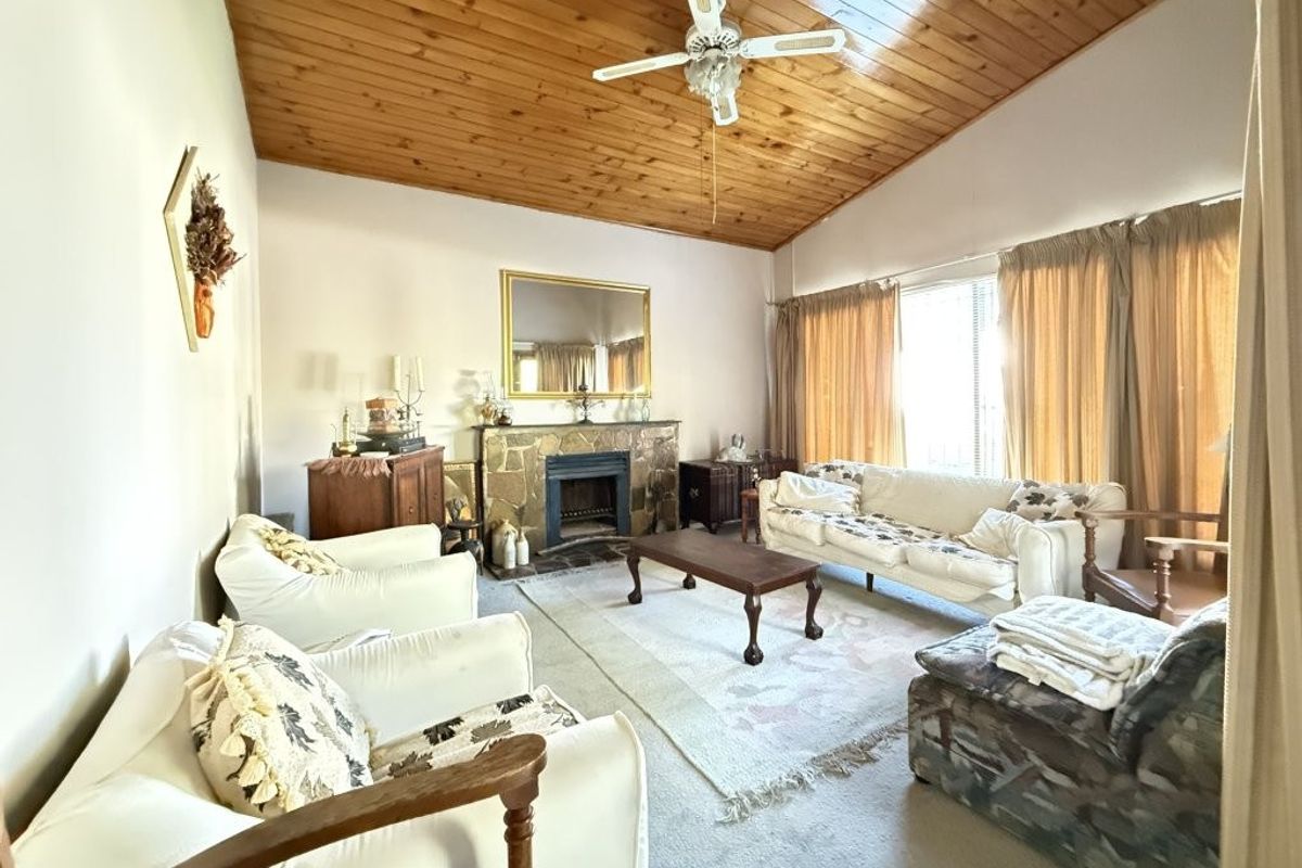 Spacious living room featuring a stone fireplace and a high timber-clad vaulted ceiling with an integrated ceiling fan.