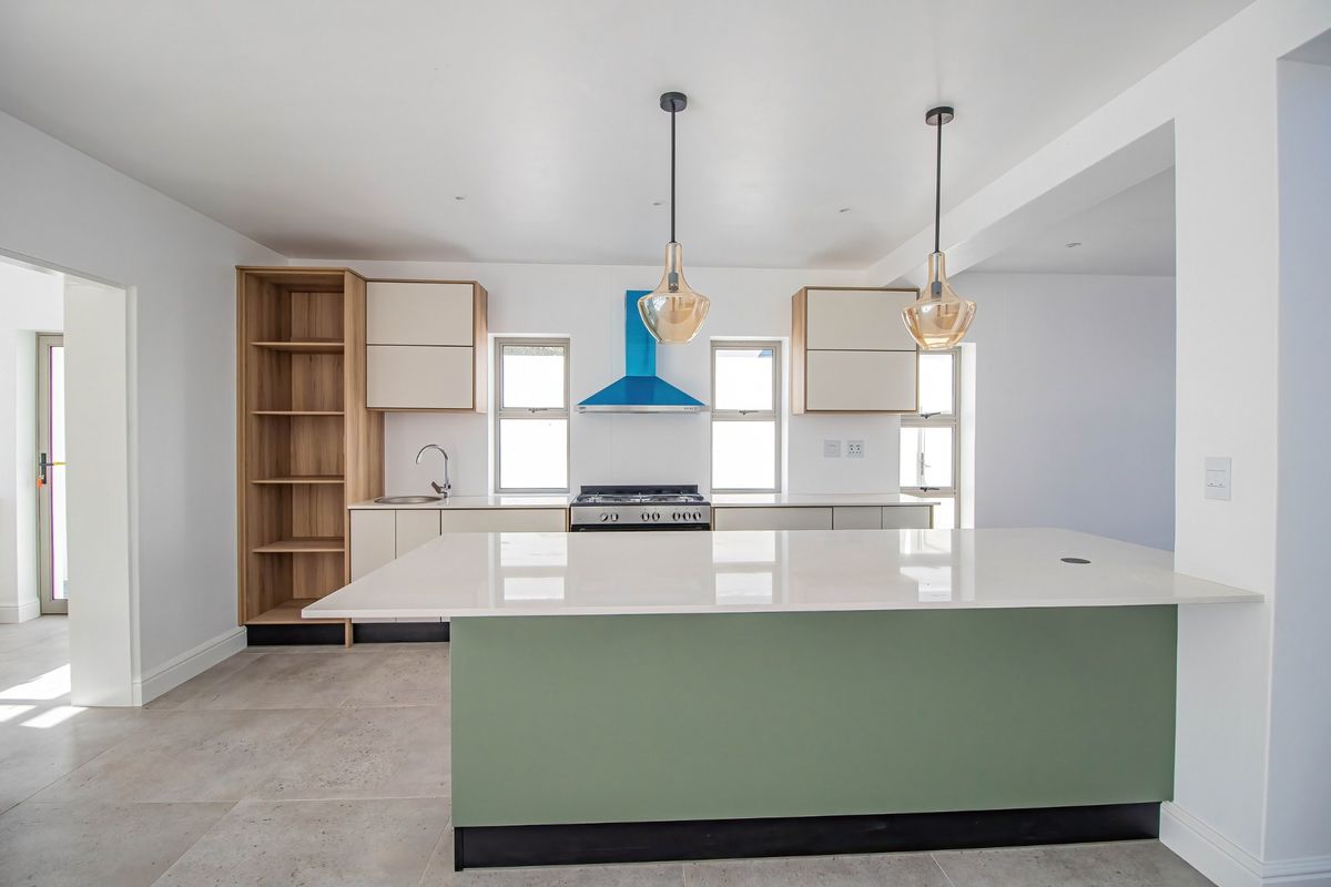 Modern kitchen featuring a central island with quartz countertops, sleek cabinetry, gas stove, extractor fan, and neutral tiled flooring in a bright, open space.