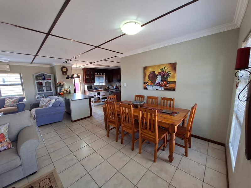 Open-plan living and dining area featuring tiled flooring, a central kitchen island, and a distinctive grid-patterned ceiling.