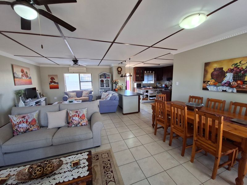 Spacious open-plan living, dining, and kitchen area featuring tiled flooring, a central kitchen island, and ceiling fans throughout.