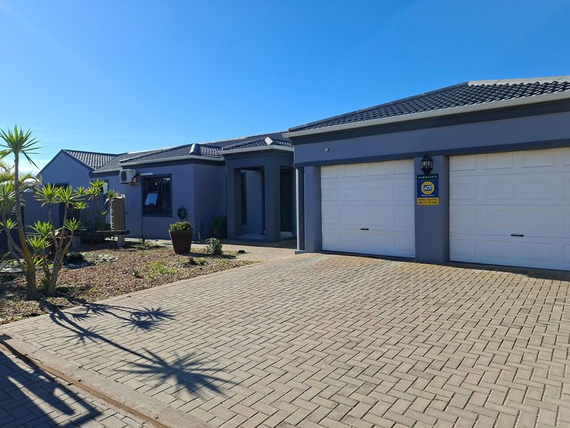 Front elevation of a modern house featuring a paved driveway, double garage, and well-maintained exterior finishes under a clear blue sky.