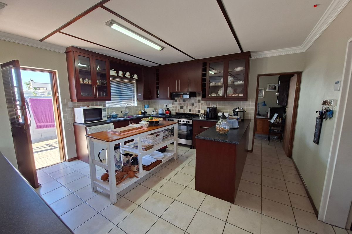 A functional kitchen featuring dark wood cabinetry, a central island, tiled flooring, and direct access to an outdoor patio area.