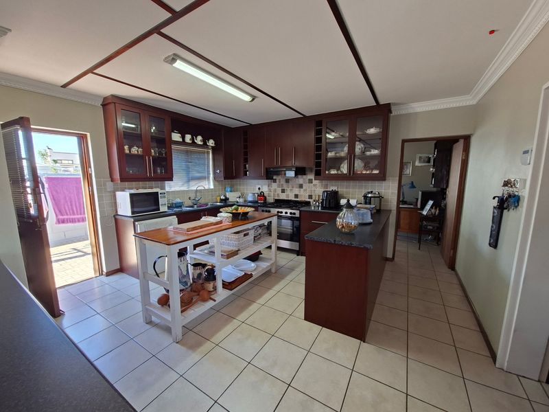 A functional kitchen featuring dark wood cabinetry, a central island, tiled flooring, and direct access to an outdoor patio area.