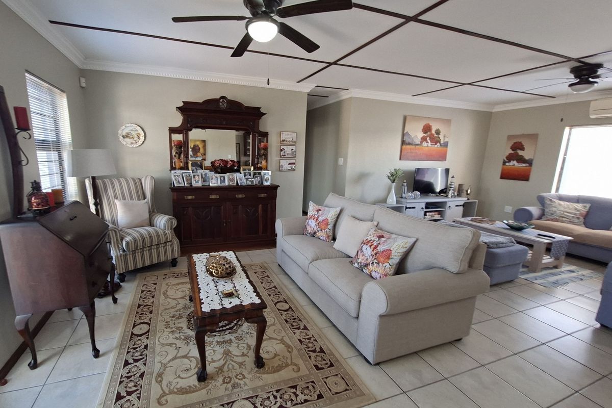 Spacious living room featuring tiled flooring, crown molding, and a distinctive grid-pattern ceiling design with integrated ceiling fans.