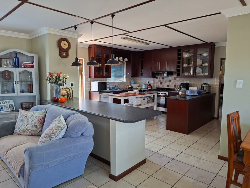 Open-plan kitchen and living area featuring dark wood cabinetry, tiled flooring, and a functional breakfast bar layout.