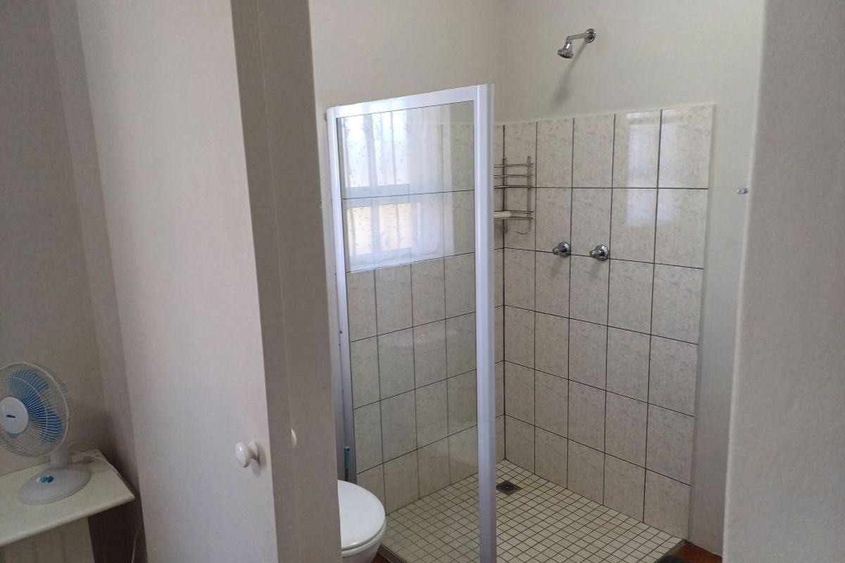 A functional bathroom featuring a walk-in shower with a glass enclosure, tiled walls, and a standard toilet.