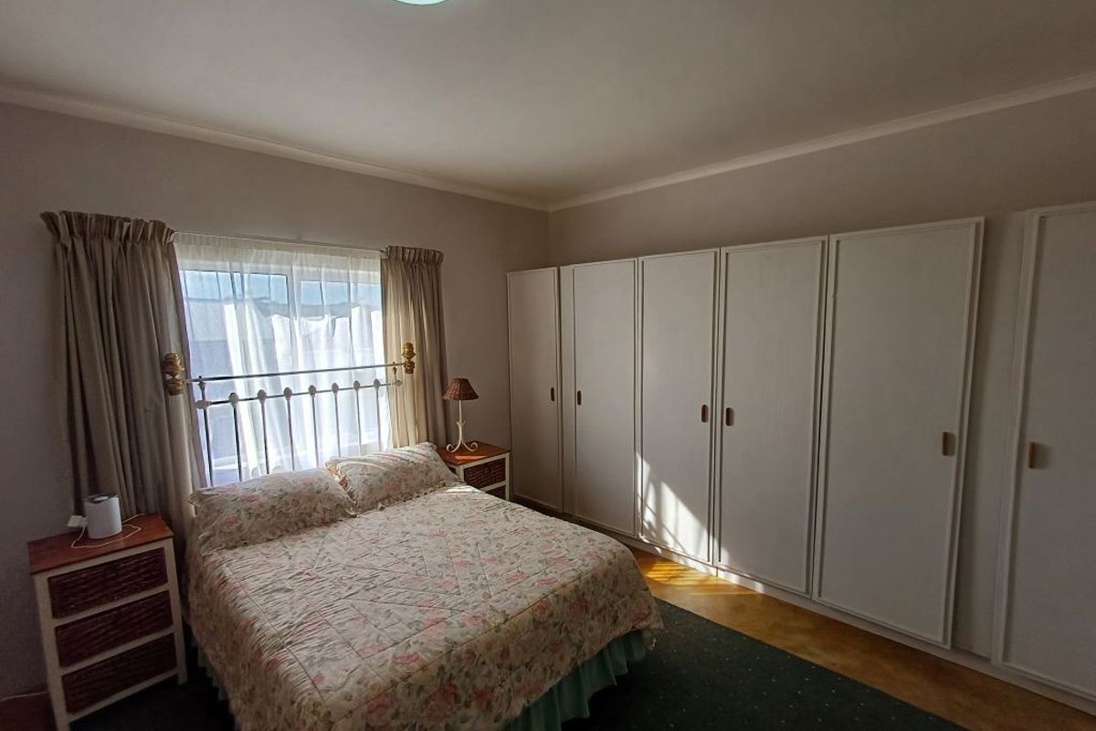 A bedroom featuring built-in cupboards and natural light, offering a functional space with potential for modern updates.