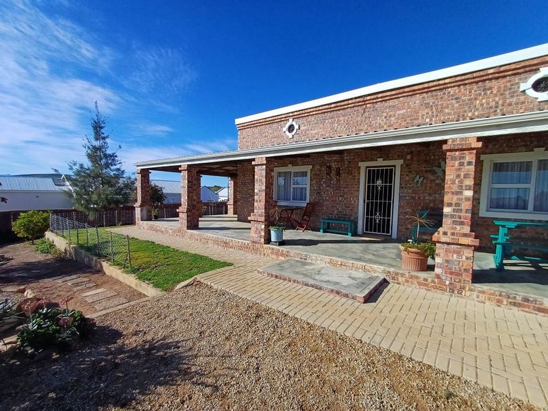 A well-maintained face brick exterior featuring a spacious covered patio, paved walkways, and a secure entrance, set within a neat garden area.