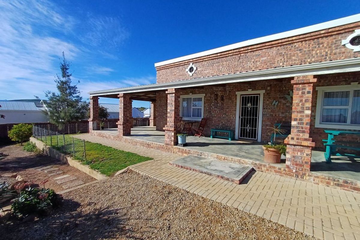 A well-maintained face brick exterior featuring a spacious covered patio, paved walkways, and a secure entrance, set within a neat garden area.