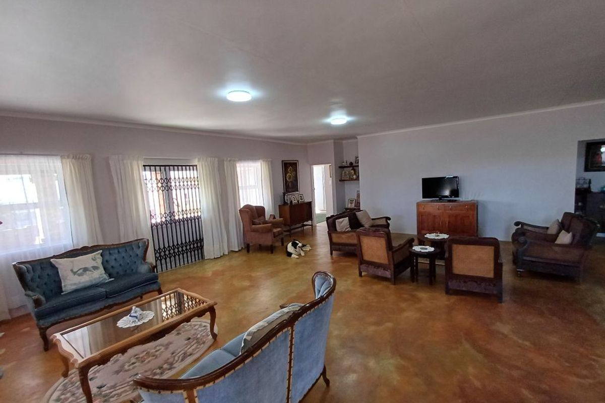 Spacious living room featuring polished concrete flooring and recessed ceiling lighting, offering a versatile open-plan layout with ample natural light.