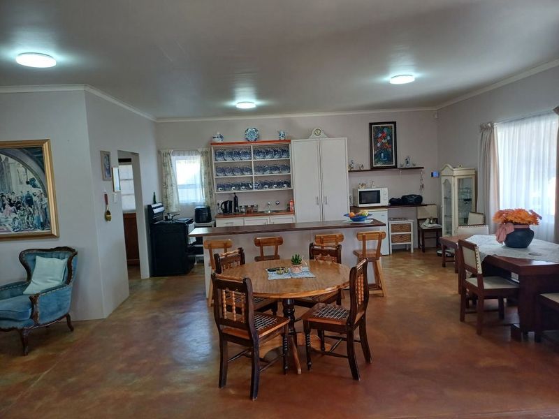 Spacious open-plan living and kitchen area featuring a breakfast bar, built-in cabinetry, and durable concrete flooring, offering a functional and versatile layout.