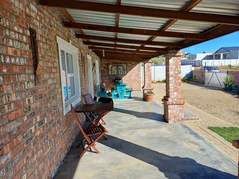 A covered outdoor patio featuring exposed brick walls, sturdy brick columns, and a timber-framed corrugated metal roof, providing a functional space for outdoor living.