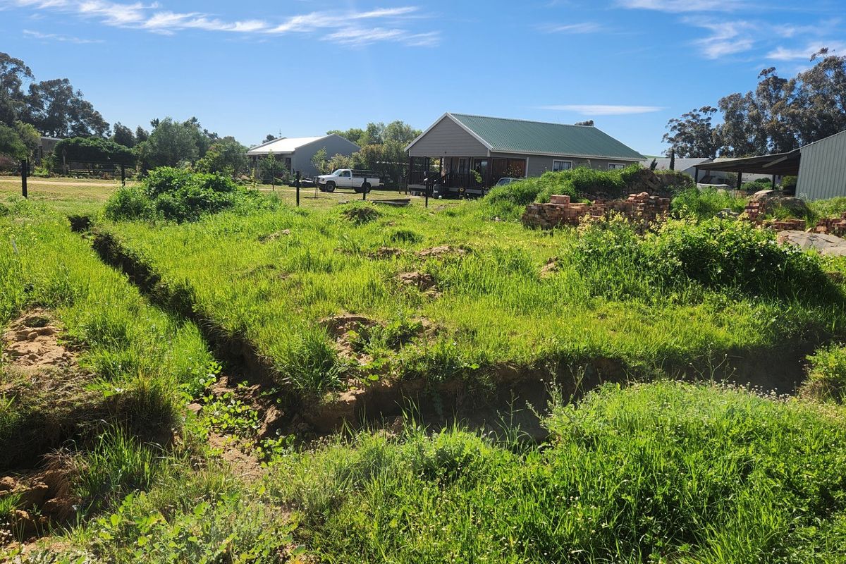 A vacant residential plot featuring excavated foundation trenches, overgrown grass, and existing boundary fencing, offering potential for new construction.