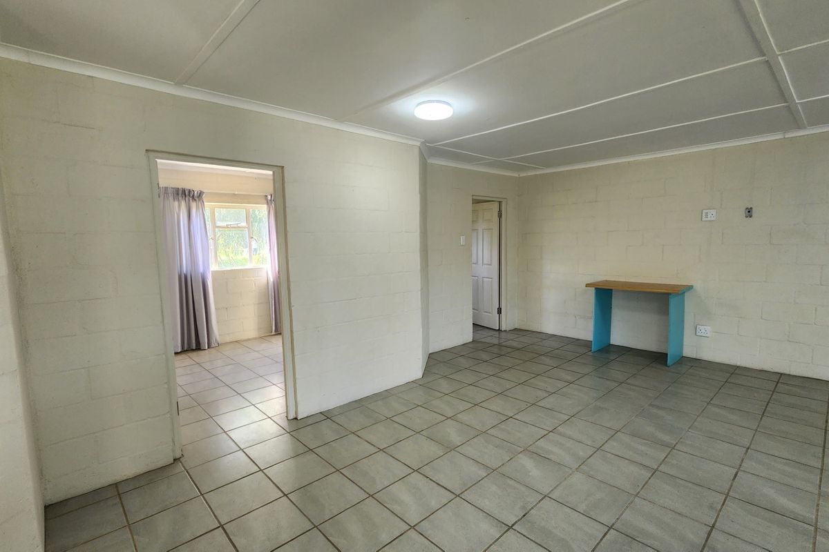 An empty living area featuring tiled flooring and exposed blockwork walls, offering a blank canvas for renovation and interior design updates.