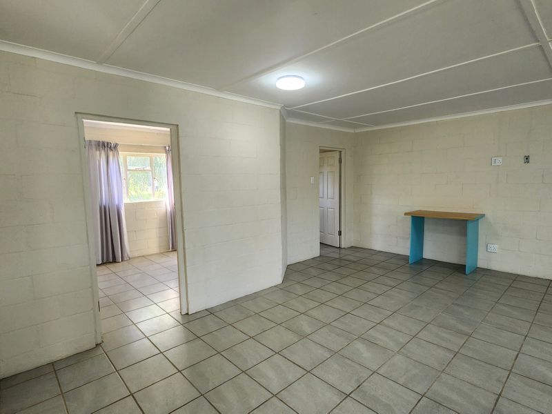 An empty living area featuring tiled flooring and exposed blockwork walls, offering a blank canvas for renovation and interior design updates.