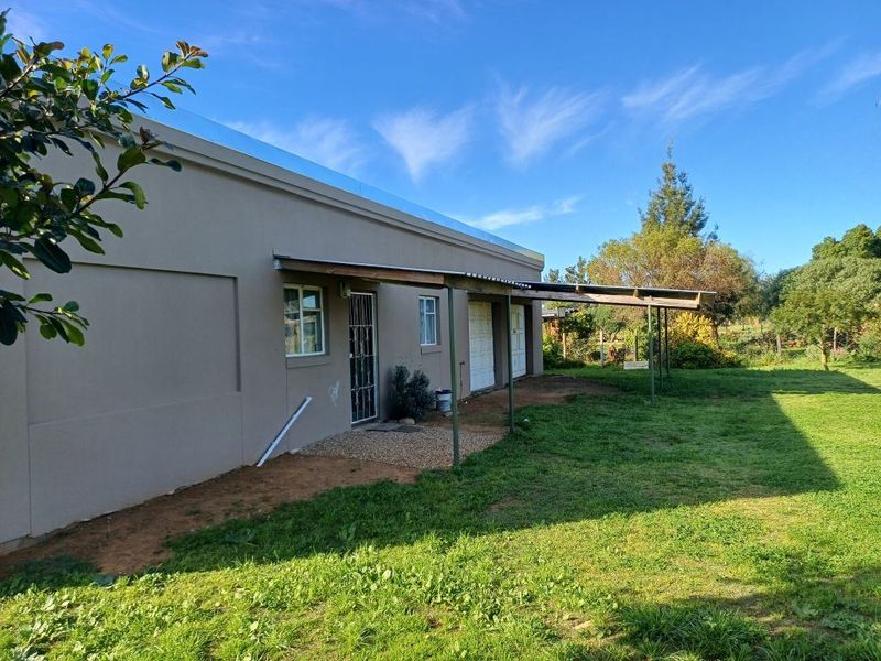 Rear view of the property featuring a lean-to patio structure, garage access, and established garden space.