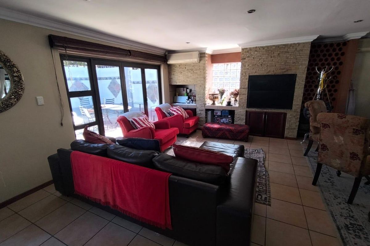 Spacious living room featuring a stone-clad feature wall, built-in cabinetry, tiled flooring, and large sliding glass doors providing access to the outdoor area.