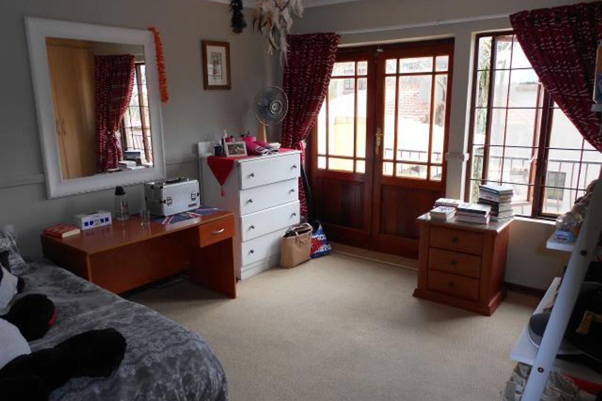 A bedroom featuring carpet flooring, built-in wardrobe, and timber-framed french doors providing access to an outdoor area.