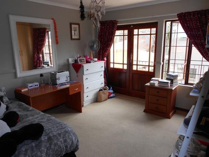 A bedroom featuring carpet flooring, built-in wardrobe, and timber-framed french doors providing access to an outdoor area.