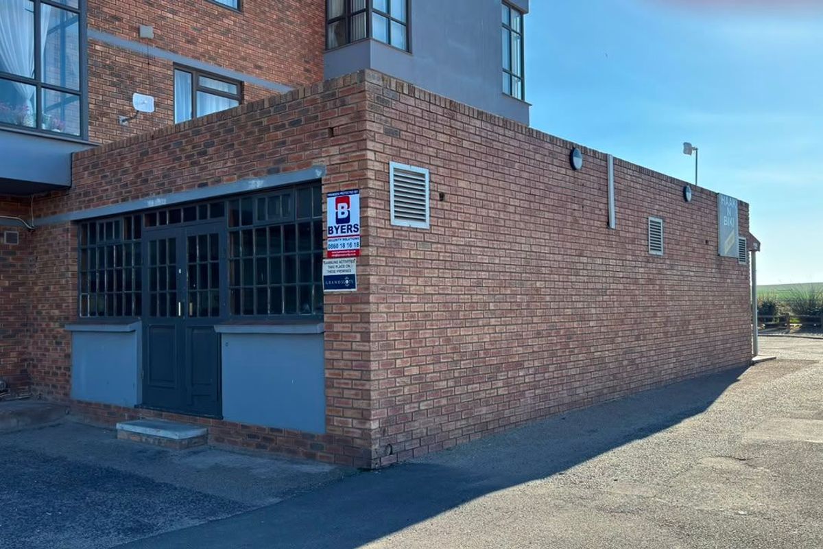 Exterior view of a commercial building featuring a brick facade, security entrance, and integrated ventilation systems.