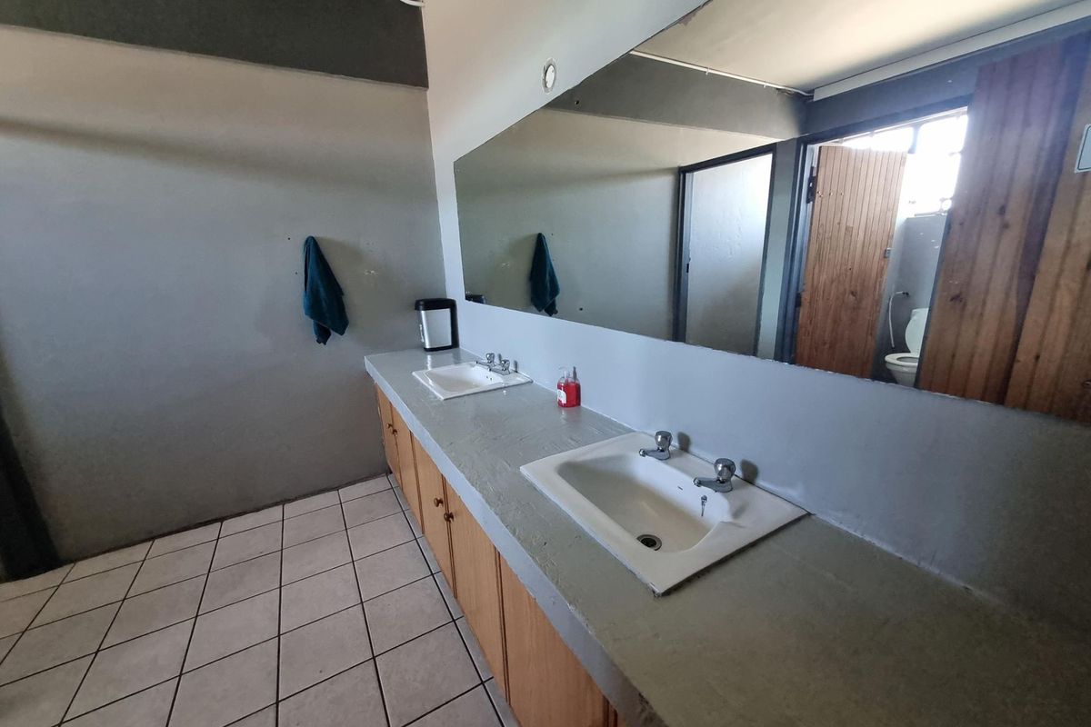 A functional bathroom featuring a double vanity with ceramic sinks, large wall mirror, and tiled flooring, offering potential for modernization.